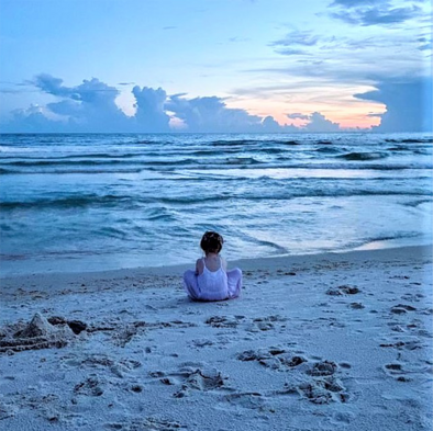 a girl sitting on the beach at the ocean